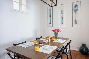 A dining table with chairs, a vase of flowers, and breakfast items.