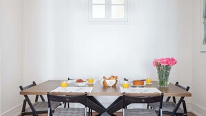 Et spisebord med stole, en vase med blomster og morgenmadsprodukter.