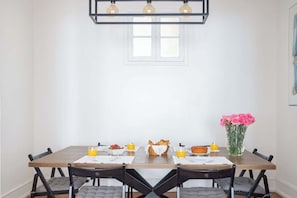 A dining table with chairs, a vase of flowers, and breakfast items.