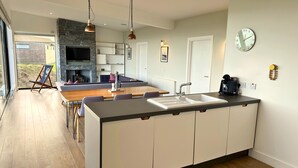 A modern kitchen with a central island, a dining area with a sofa, and a fireplace.