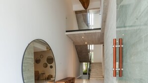 A modern interior with a marble floor, a round mirror, a wooden bench, and a staircase. - Riva Playasur 405 - luxury studio - (playa del carmen)