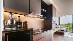 A modern kitchen with a built-in oven, a coffee machine, and a compact refrigerator. - Riva Playasur 405 - luxury studio - (playa del carmen)