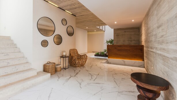 A modern interior with a marble floor, a wooden staircase, and a seating area with a woven chair. - Riva Playasur 405 - luxury studio - (playa del carmen)