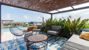 A rooftop terrace with a pool, outdoor seating, and a view of the city skyline. - Riva Playasur 405 - luxury studio - (playa del carmen)