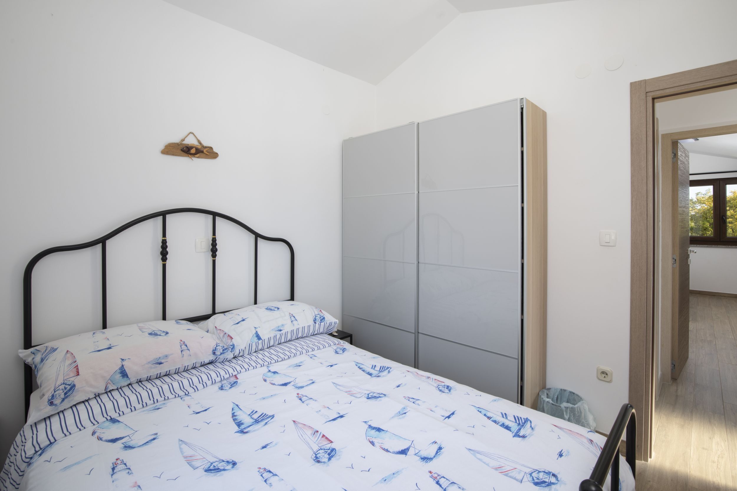 A bedroom with a bed, a wardrobe, and a small bedside table.
