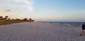 A wide sandy beach with people walking and relaxing.