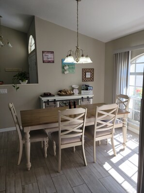 Un'area pranzo con un tavolo e sedie in legno, un lampadario e una finestra con tende.
