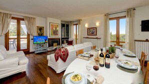 A dining area with a table set for a meal, a sofa, a television, and a fireplace.