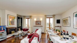 A living room with a sofa, a TV, a fireplace, and a dining area with a table set for two.