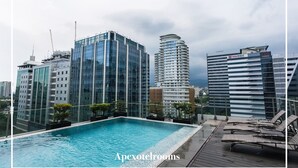 Une piscine sur le toit, avec des immeubles modernes en arrière-plan.