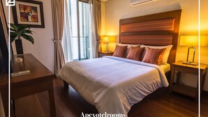 Une chambre d’hôtel comprenant un lit, des lampes de chevet, un bureau avec une télécommande, une plante en pot et un appareil de climatisation.