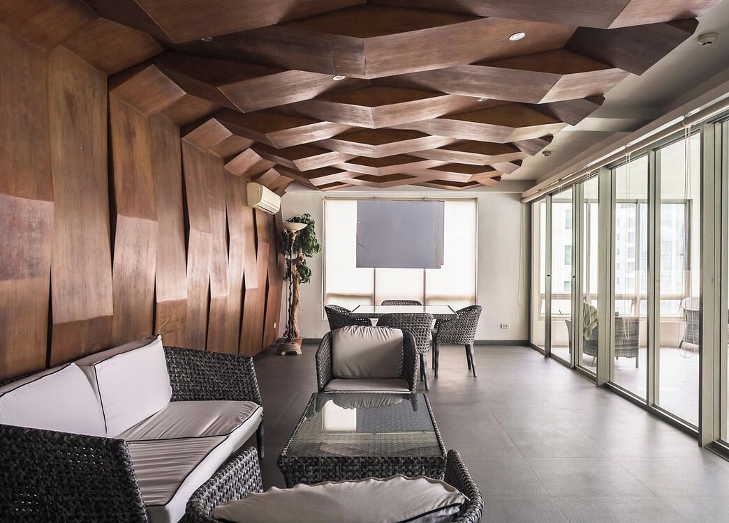 Ein modernes Interieur mit einer geometrischen Decke, einer Couch, einem Esstisch und großen Fenstern.