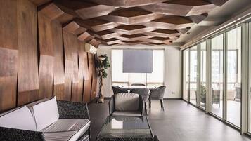 Ein modernes Interieur mit einer geometrischen Decke, einer Couch, einem Esstisch und großen Fenstern.