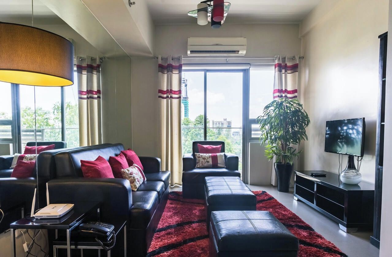 A modern living room with a sofa, ottoman, and a TV on a stand.