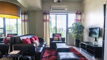 A modern living room with a sofa, ottoman, and a TV on a stand.