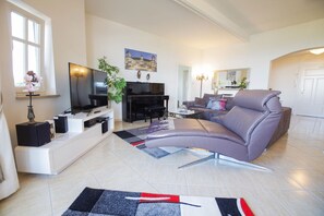 Una sala de estar moderna con un sofá, televisor y un piano.