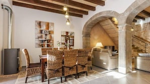 A dining area with wicker chairs and a table, a sofa, and a stone fireplace. - Can Bodeguita, Wifi, Private pool and terrace. (Binissalem)