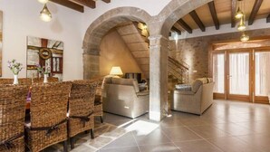 A spacious living area with a high ceiling, stone arches, and a fireplace. There are two sofas and a dining table with wicker chairs. - Can Bodeguita, Wifi, Private pool and terrace. (Binissalem)