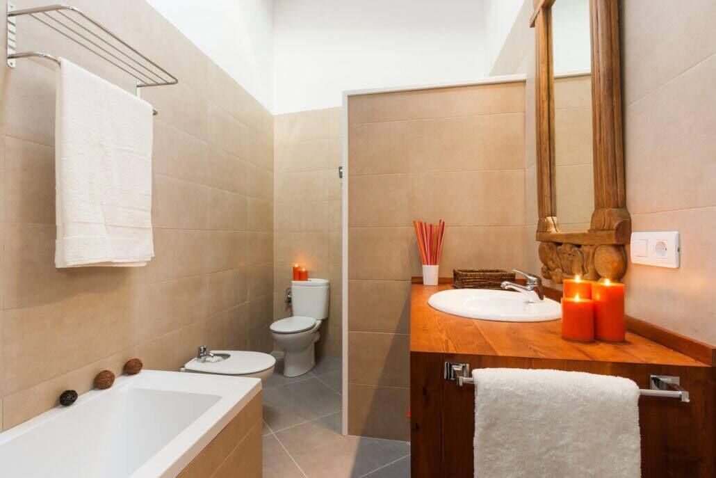 A modern bathroom with a bathtub, two sinks, a toilet, and a vanity with a mirror.