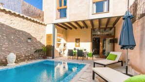A poolside area with a stone wall, a white statue, and a lounge chair with a green pillow. - Can Bodeguita, Wifi, Private pool and terrace. (Binissalem)
