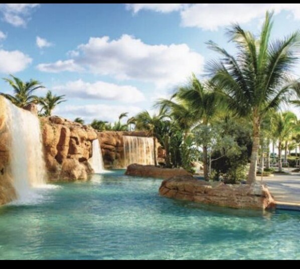 Relax by the resort's tranquil pool, surrounded by a natural rock formation and a soothing waterfall.