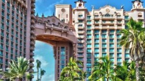 A resort with a large pool, palm trees, and a bridge connecting buildings. - Vacation Rental Villa sleeps 4;Harborside Resort at Atlantis, Bahamas; Dec16-21 (Paradise Island)