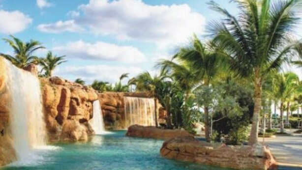 A pool with a waterfall and palm trees. - Vacation Rental Villa sleeps 4;Harborside Resort at Atlantis, Bahamas; Dec16-21 (Paradise Island)