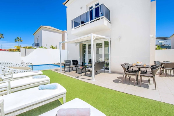 Ein moderner Poolbereich im Freien mit Liegestühlen und einer überdachten Lounge.