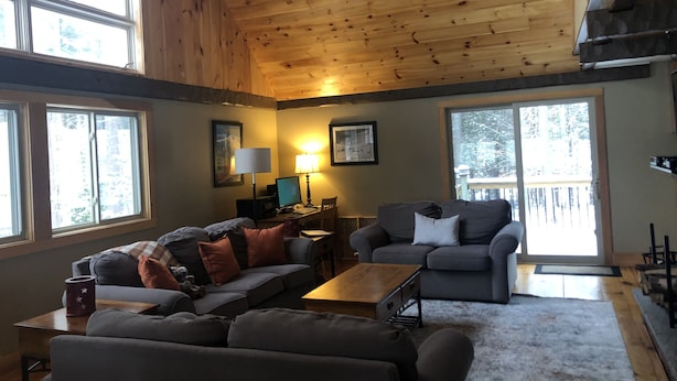 Ein gemütliches Wohnzimmer mit Holzboden, zwei Sofas, einem Couchtisch und einem Kamin.