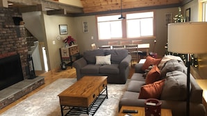 Ein gemütliches Wohnzimmer mit Kamin, einer Sofagarnitur, einem Couchtisch und einem Essbereich mit Stühlen und Tisch.