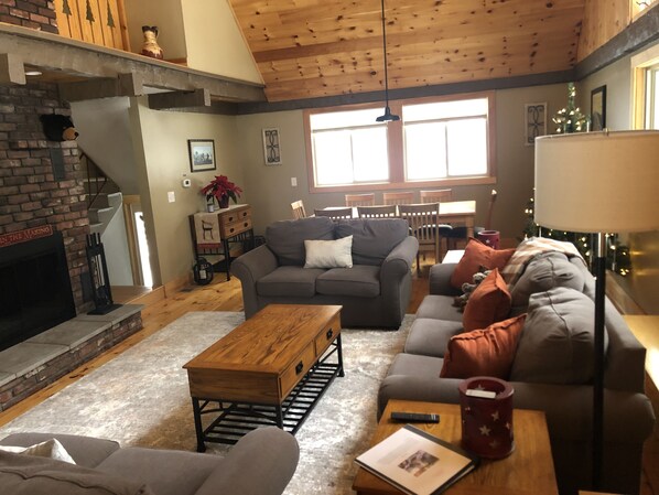 A cozy living room with a fireplace, a sofa set, a coffee table, and a dining area with chairs and a table.