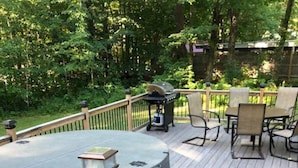 Eine Holzterrasse mit Whirlpool, Gartenmöbeln und einem Blumenbeet.