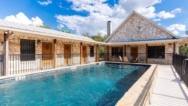 A swimming pool with a stone facade and a covered patio area. - Vacation Home with pool located in Cypress Bend (Concan)
