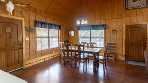 A wooden interior with a dining table and chairs, a chandelier, and a door with a cow skull decoration. - Vacation Home with pool located in Cypress Bend (Concan)