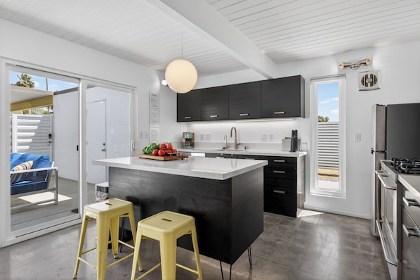 Una cocina moderna con una isla central, armarios negros y un ventanal amplio.