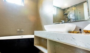 Enjoy a relaxing soak in the bathtub, paired with a large mirror and sleek sink area.