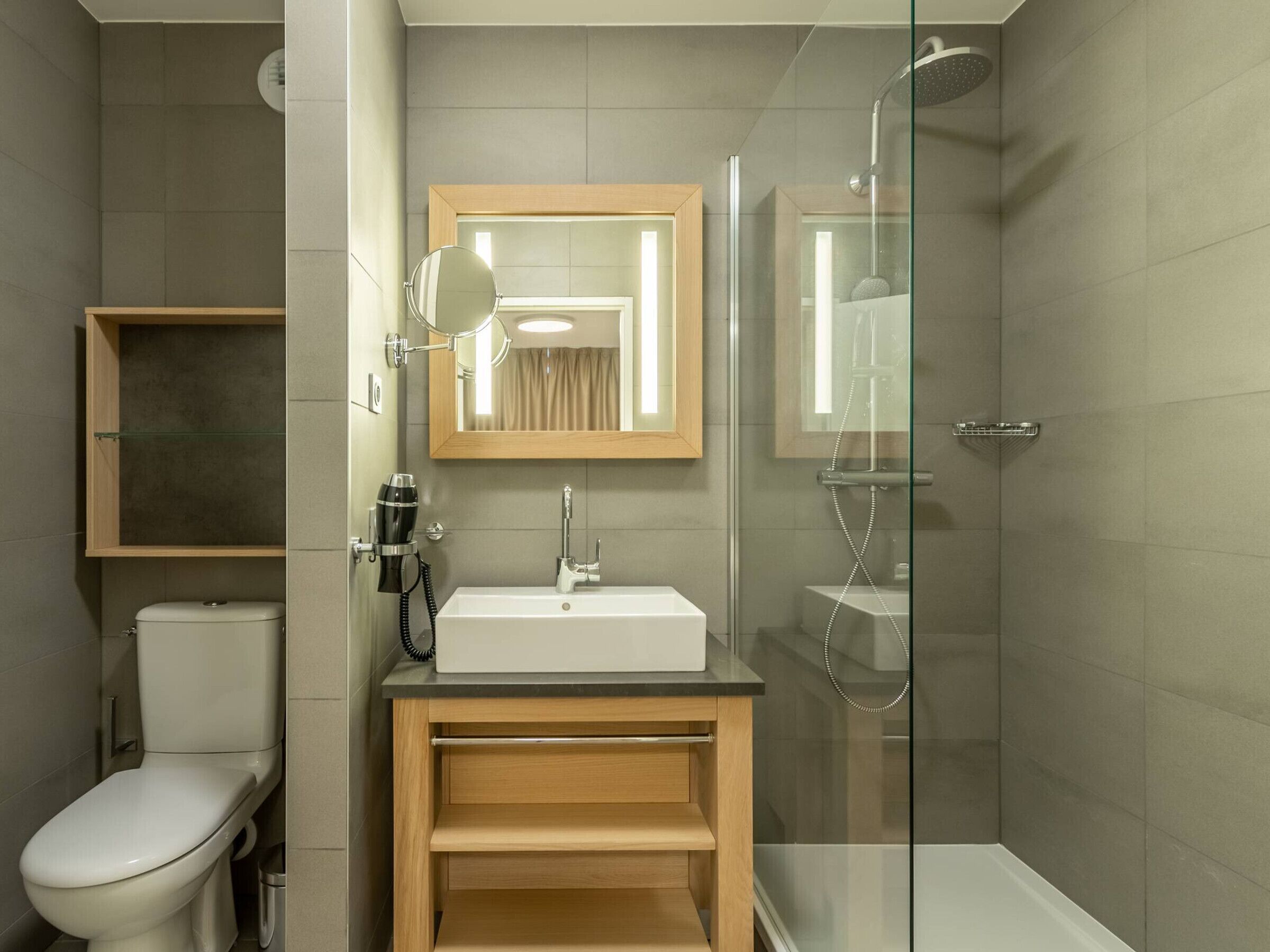 Un bagno moderno con servizi igienici, lavandino, specchio e cabina doccia in vetro.