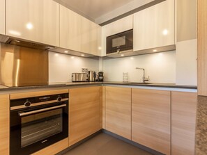 Enjoy cooking in this well-equipped kitchen with a range hood, microwave, oven, and ample countertop space.