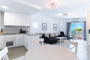 A modern kitchen with white cabinets, a coffee machine, and a dining area with a round table and chairs.