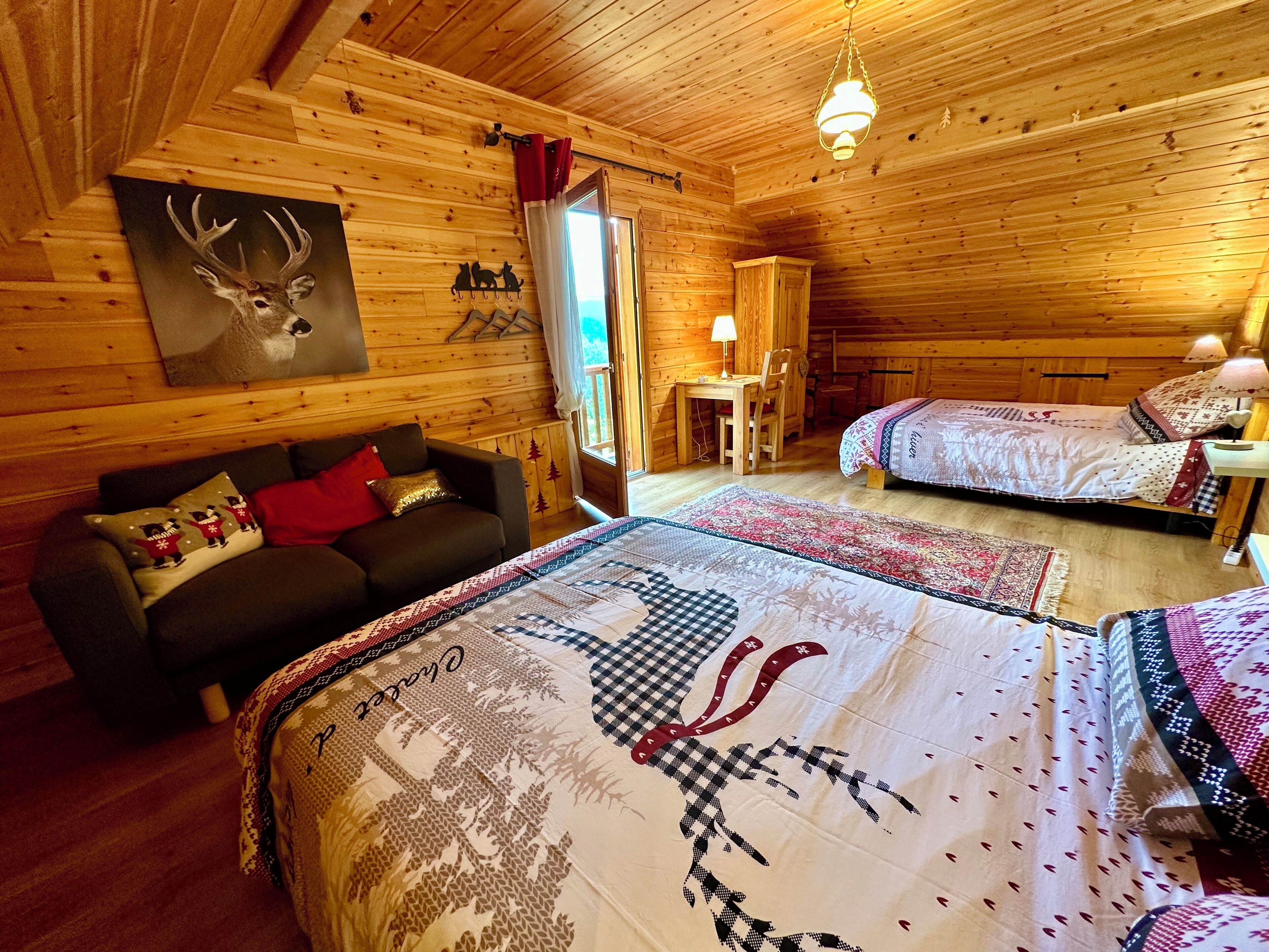 Un chalet confortable avec deux lits, un canapé, un coin repas et une grande fenêtre.