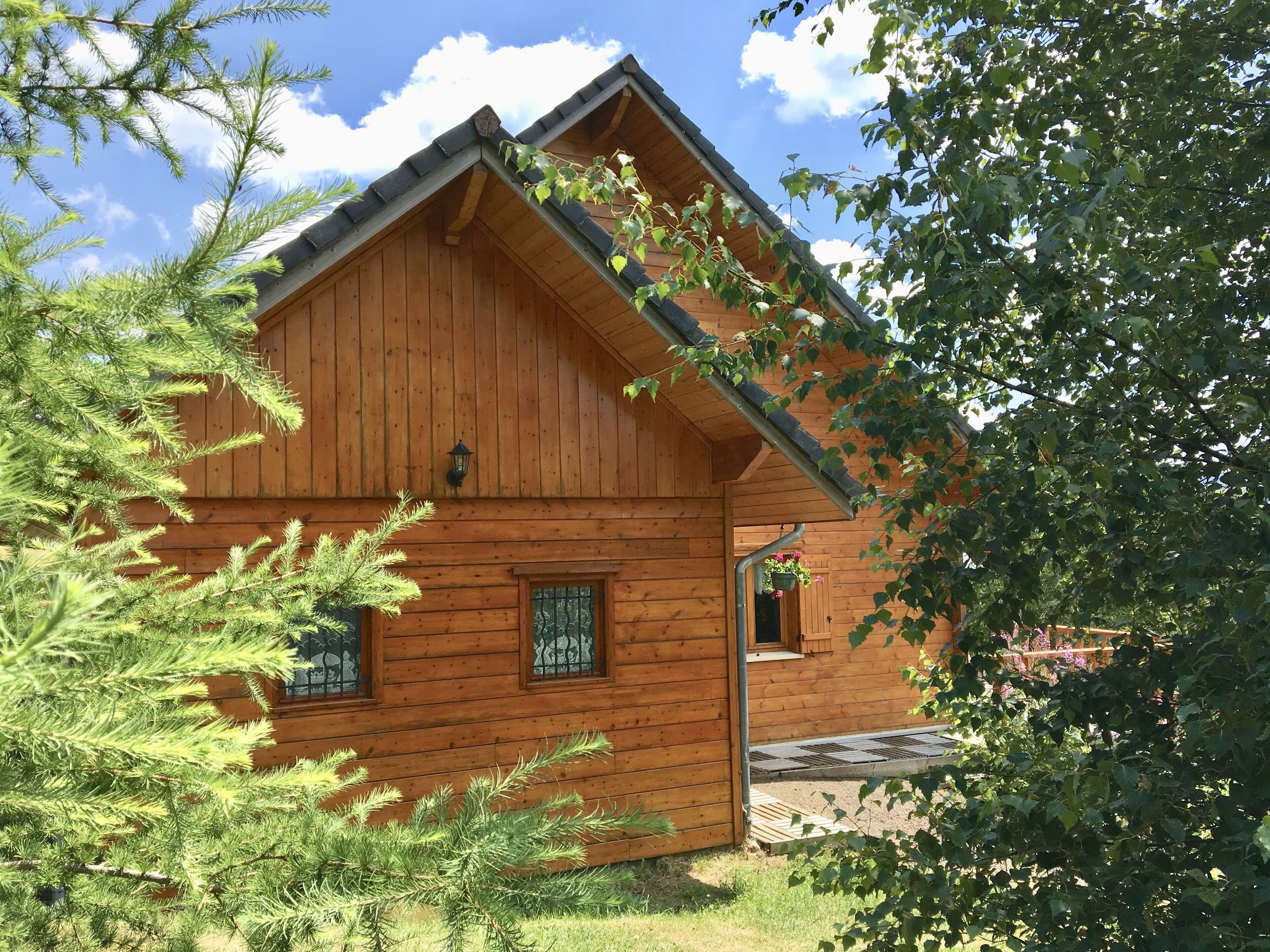 A wooden cabin with a gabled roof, a small porch, and a window with a metal grill.