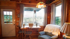 Un interior de cabaña acogedor con una mesa de comedor de madera, sillas, un sofá y una lámpara.