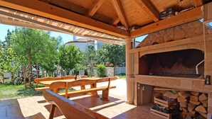 An outdoor patio with a wooden bench and a stone fireplace. - Beautiful apartment for 6 guests with WIFI, pool, A/C, TV and terrace (Zadar)
