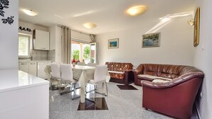 A modern living room with a dining area, a brown leather sofa, and a kitchen with white cabinets. - Beautiful apartment for 6 guests with WIFI, pool, A/C, TV and terrace (Zadar)
