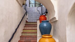 A staircase with patterned steps leading to a landing, a decorative archway, and a row of colorful vases. - Iconic, Unique Home in the Heart of Downtown SB! (Santa Barbara)