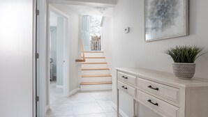 Ein Flur mit Treppe, einem weißen Schrank mit Schubladen und einer Zimmerpflanze.