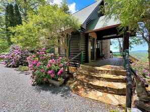 A cabin with a stone foundation, a wooden deck, and a porch with a stone staircase. - Cabin Fever- Pet Friendly | Secluded Home | Screened Porch (Morganton)