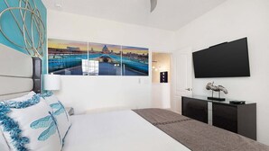 A modern hotel room with a large bed, a flat-screen TV, a cityscape mural, and a desk with a lamp. - Unreal Home Near Disney w/ Volcano & Space Theme BRs, Theater, Arcade, Game RM (Davenport)