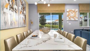 A dining area with a marble table, leather chairs, and artwork on the walls. - Unreal Home Near Disney w/ Volcano & Space Theme BRs, Theater, Arcade, Game RM (Davenport)