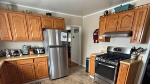 A kitchen with wooden cabinets, a stainless steel refrigerator, a stove, and a microwave. - Pappys place at Smoke Hole (Upper Tract)
